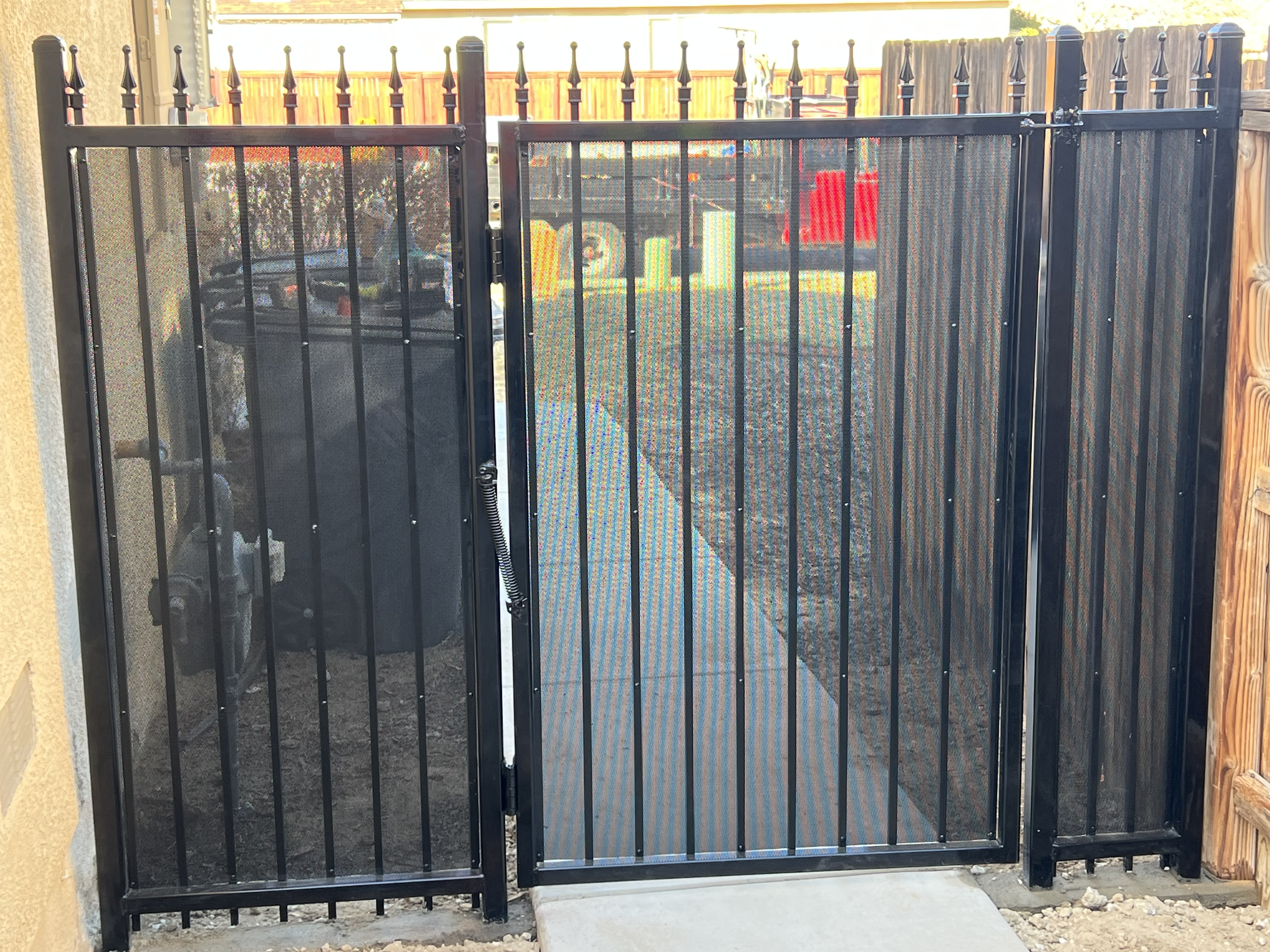 Black ornamental iron gate with spear finials and privacy mesh screen