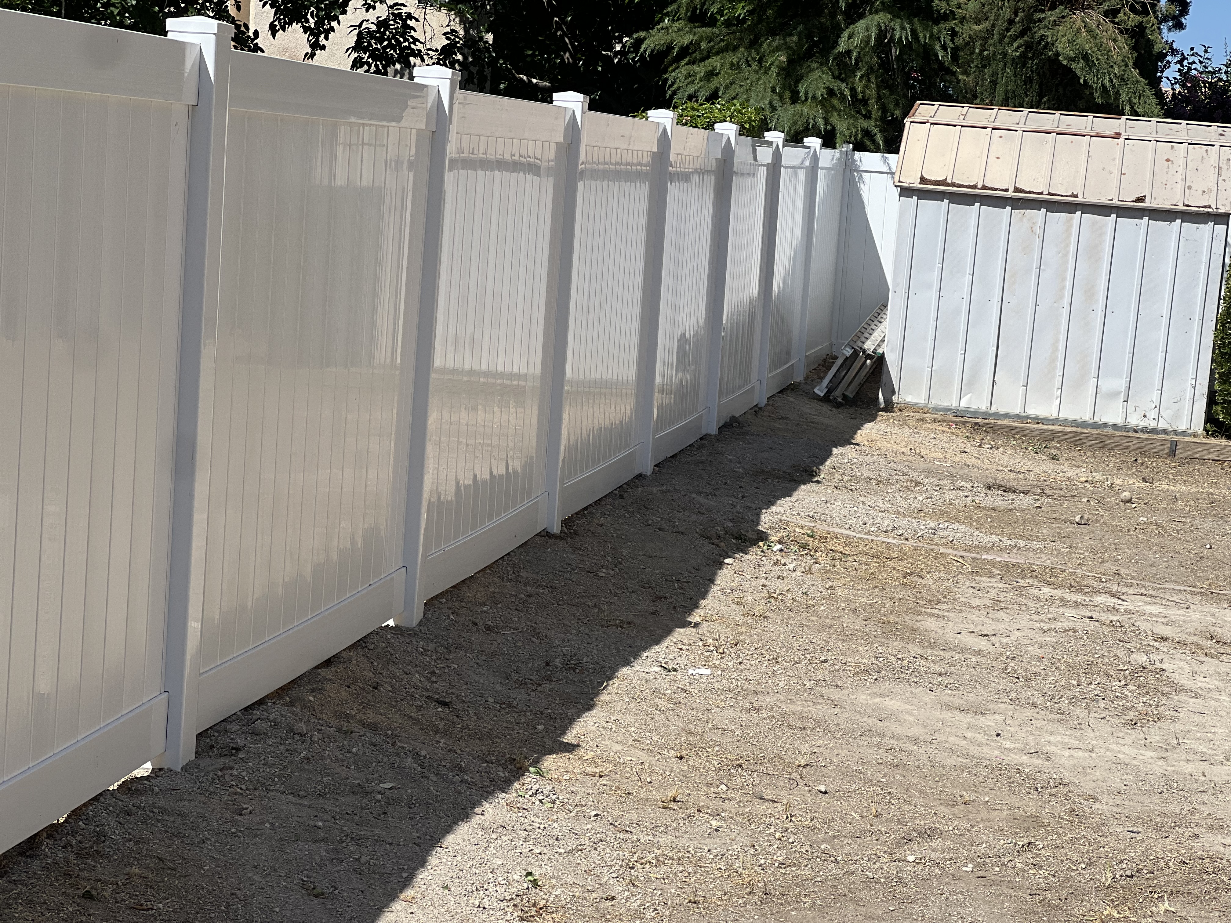 Long white vinyl privacy fence run along commercial side yard