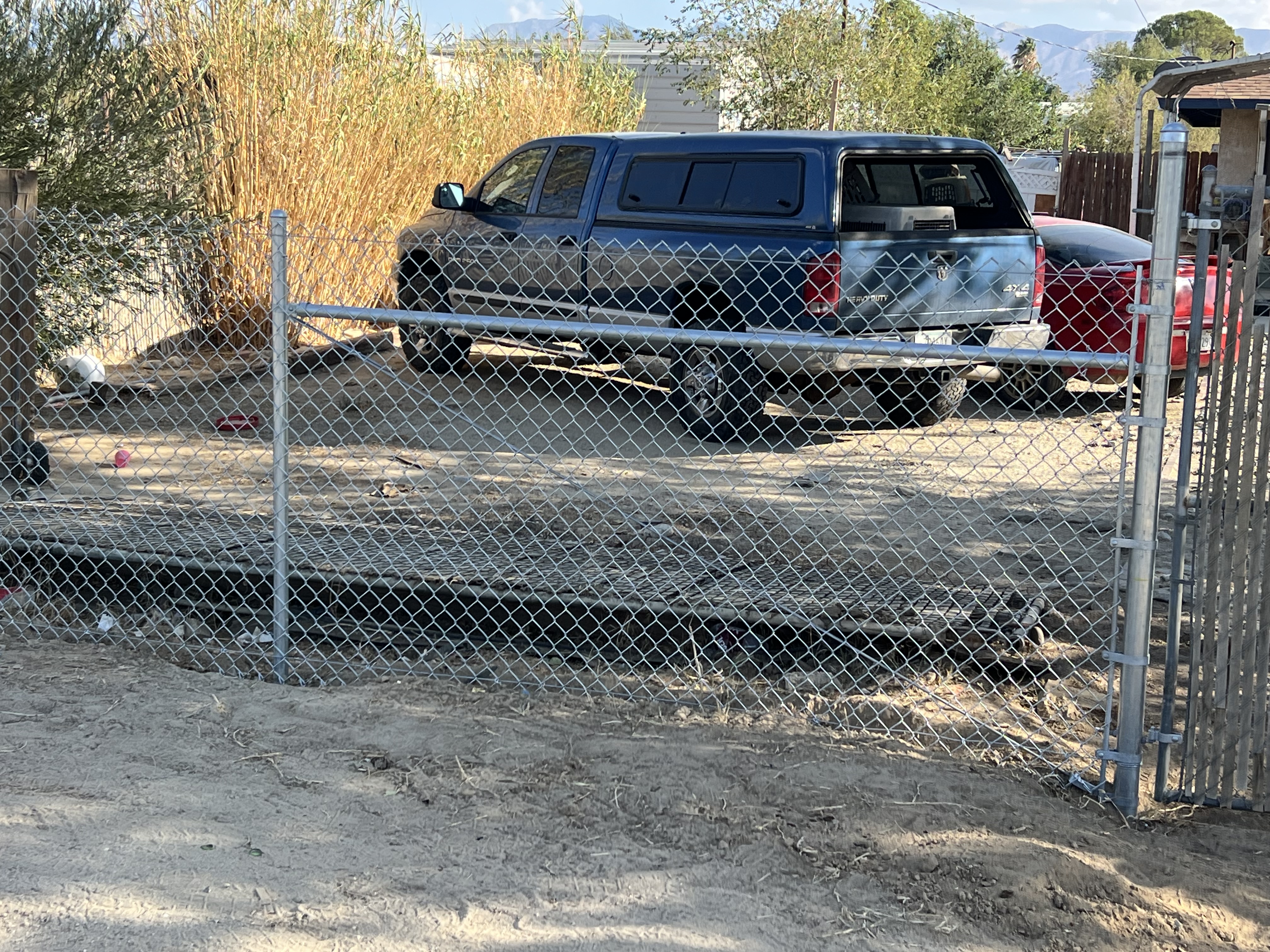 Chain-link gate section — wide desert landscape with mountains and solar panels in background