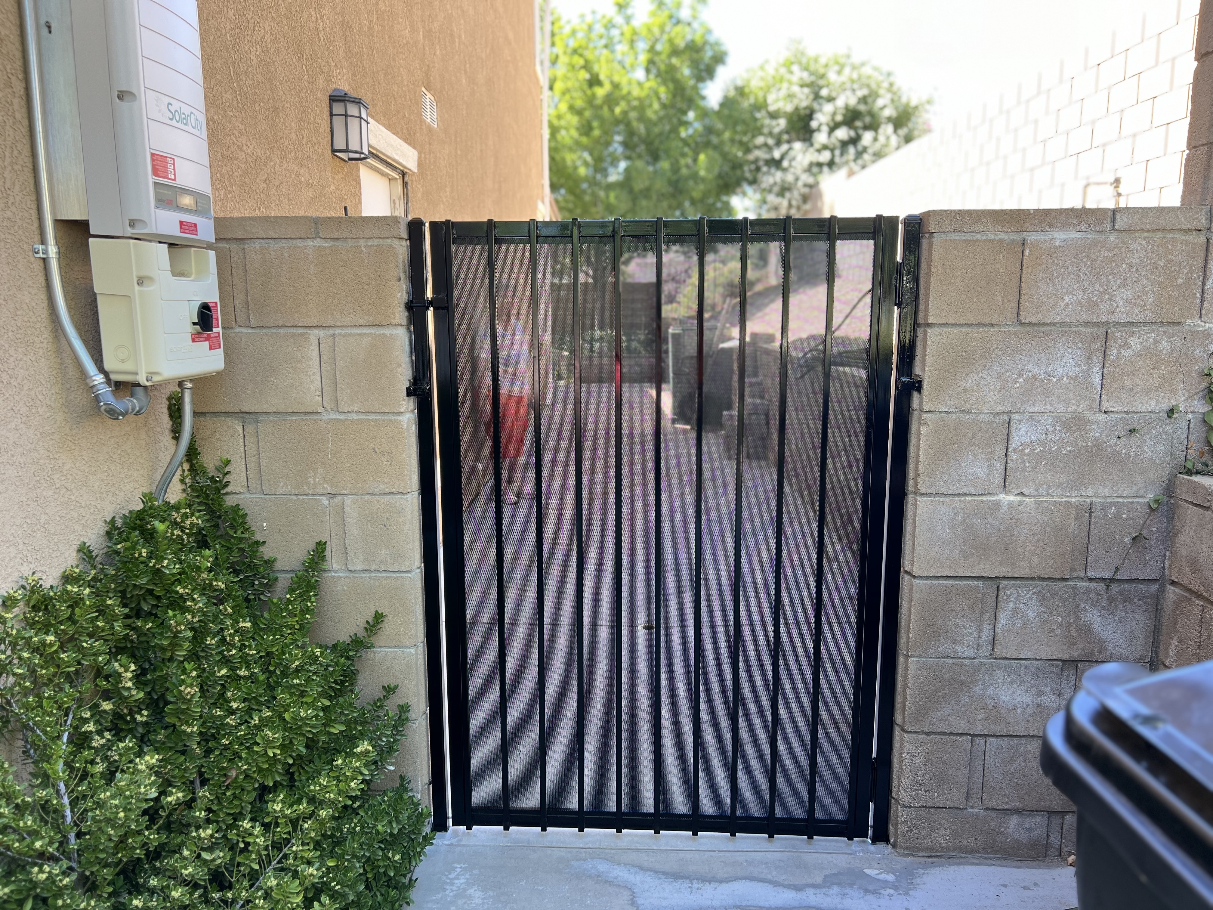 Black wrought iron pedestrian gate with mesh screen